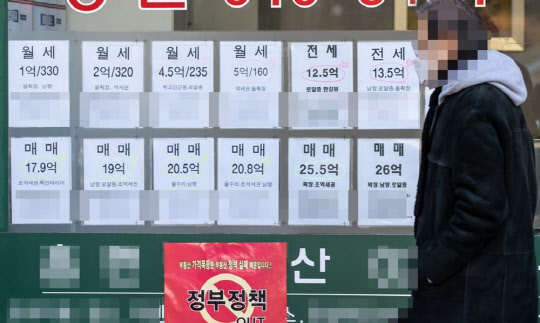 한 시민이 부동산 시세가 붙은 부동산공인중개업소 매물정보 게시판 앞을 지나가고 있다.   연합뉴스